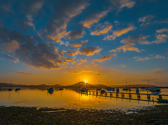 Aerial sunrise waterscape with boats, reflections and low cloud