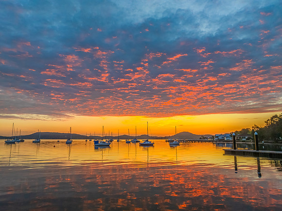 Aerial sunrise over the water with boats and clouds