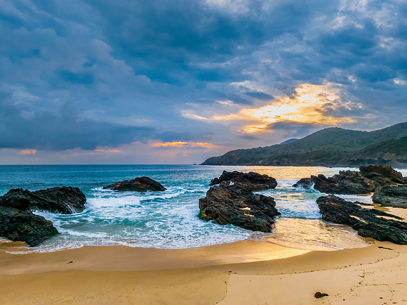 Rain clouds, rocks and sunrise at the seaside