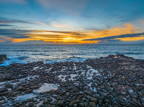 Sunrise over the sea and rock platform with high cloud