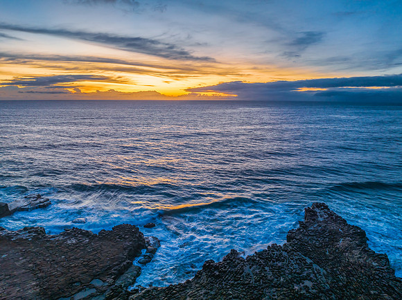 Sunrise over the sea and rock platform with high cloud