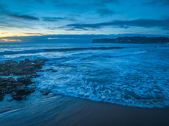 Sunrise over the sea and rock platform with high cloud