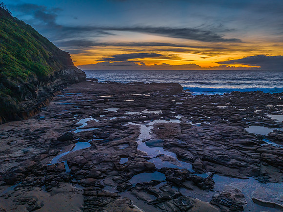 Sunrise over the sea and rock platform with high cloud
