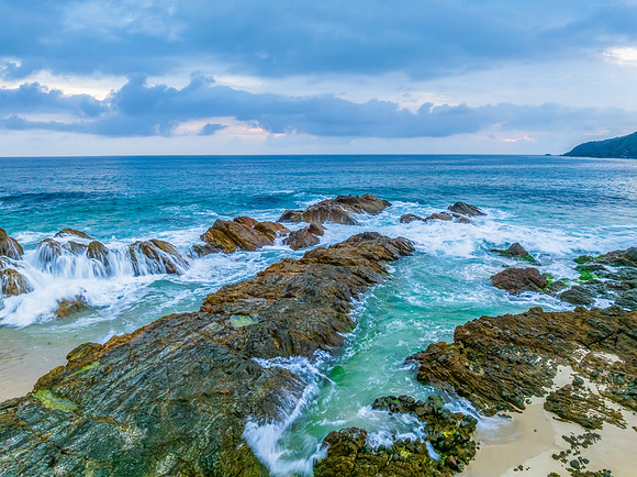 Rain clouds, rocks and sunrise at the seaside