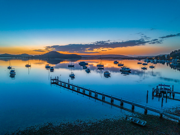 Aerial sunrise waterscape with boats, reflections and low cloud