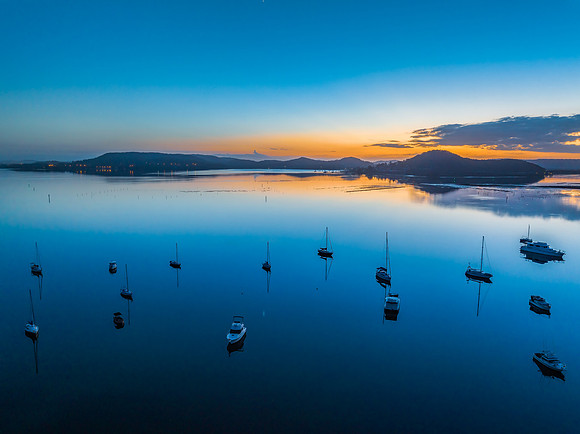 Aerial sunrise waterscape with boats, reflections and low cloud