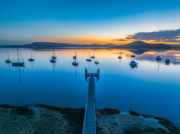 Aerial sunrise waterscape with boats, reflections and low cloud
