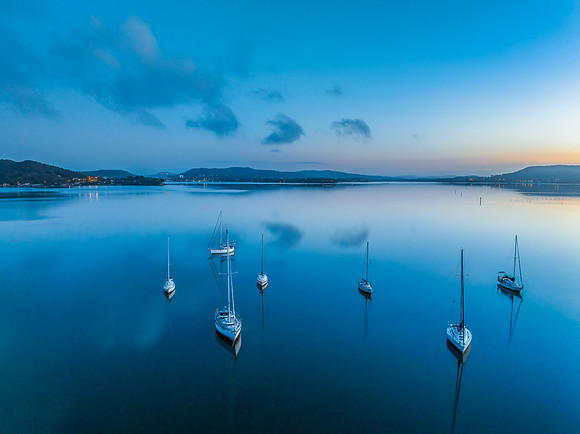 Aerial sunrise waterscape with boats, reflections and low cloud