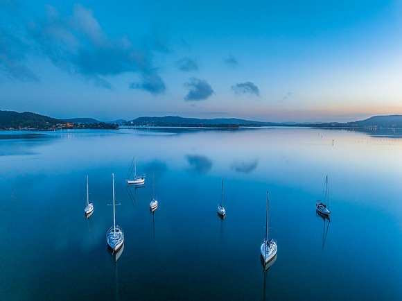 Aerial sunrise waterscape with boats, reflections and low cloud
