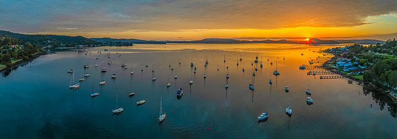 Aerial sunrise over the water with boats and clouds