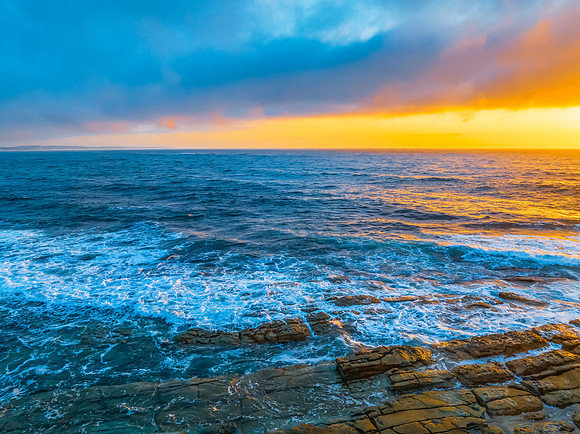 Cloudy sunrise over the ocean with rock platform
