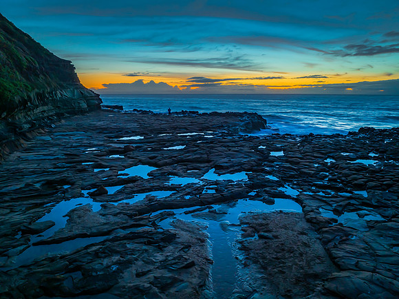 Sunrise over the sea and rock platform with high cloud