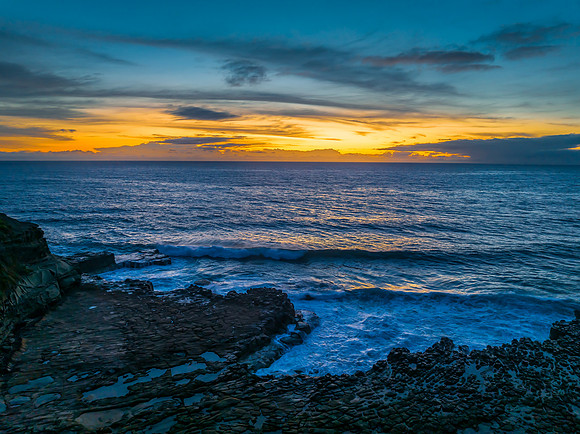 Sunrise over the sea and rock platform with high cloud