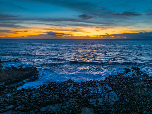 Sunrise over the sea and rock platform with high cloud