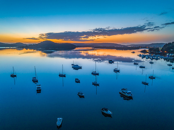 Aerial sunrise waterscape with boats, reflections and low cloud