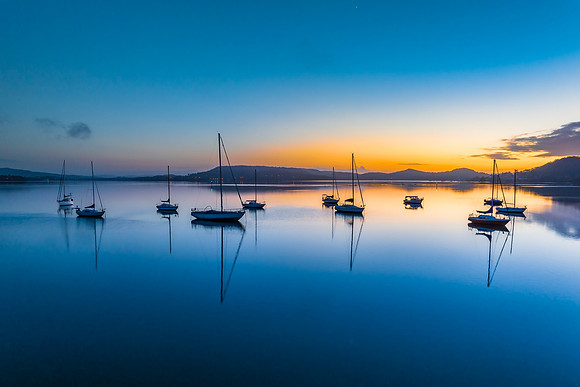Aerial sunrise waterscape with boats, reflections and low cloud