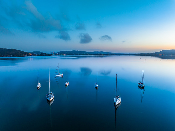 Aerial sunrise waterscape with boats, reflections and low cloud