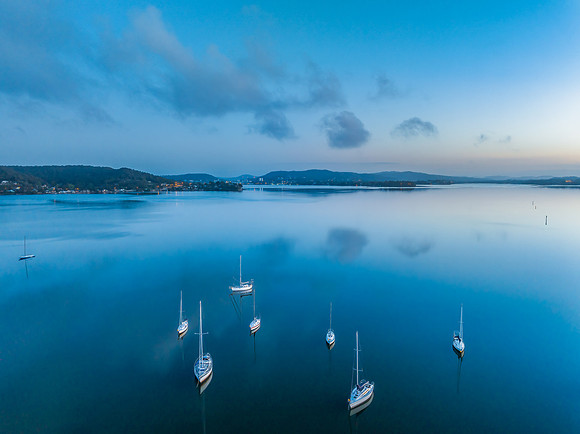 Aerial sunrise waterscape with boats, reflections and low cloud