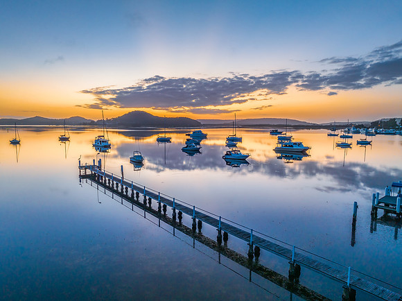 Aerial sunrise waterscape with boats, reflections and low cloud