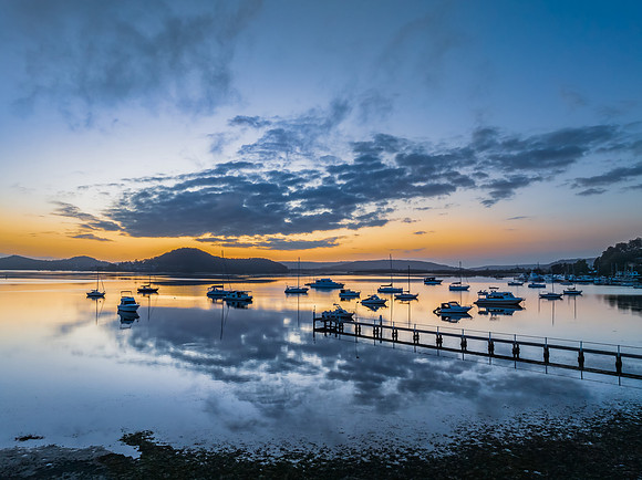 Aerial sunrise waterscape with boats, reflections and low cloud