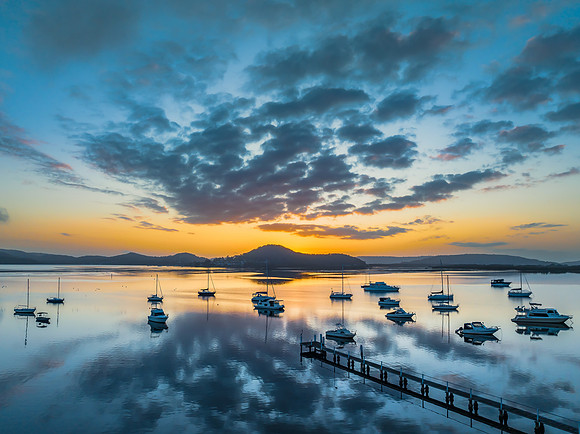 Aerial sunrise waterscape with boats, reflections and low cloud