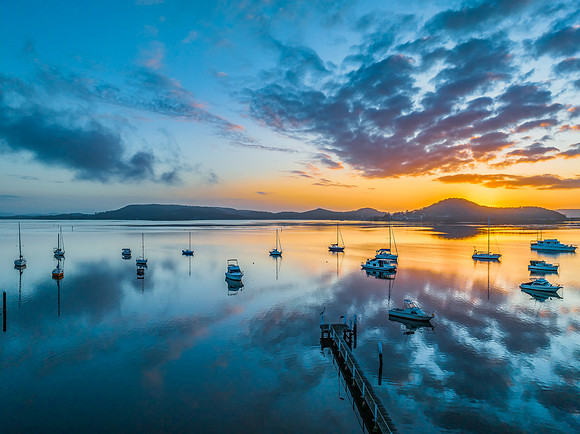 Aerial sunrise waterscape with boats, reflections and low cloud