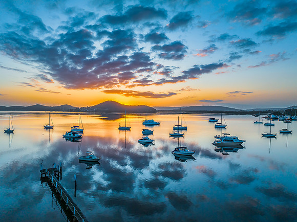 Aerial sunrise waterscape with boats, reflections and low cloud