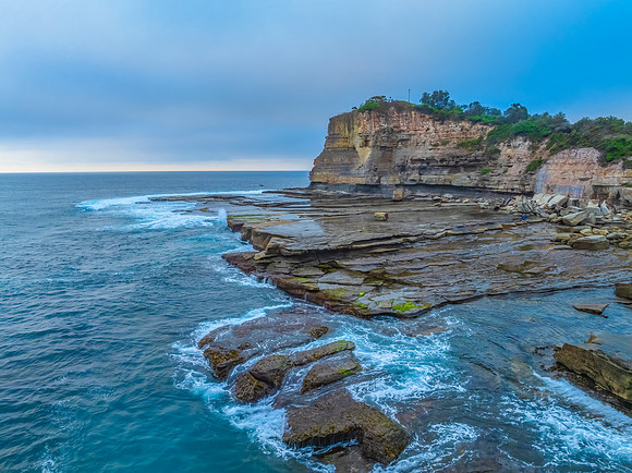 Sunrise seascape and rocky Inlet with thick fog cloud over the o
