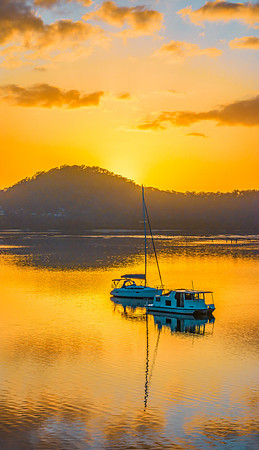 Aerial sunrise waterscape with boats, reflections and low cloud