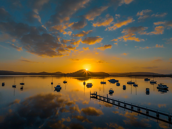 Aerial sunrise waterscape with boats, reflections and low cloud