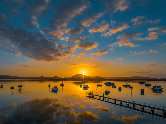 Aerial sunrise waterscape with boats, reflections and low cloud