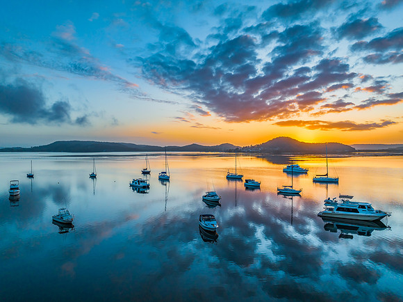 Aerial sunrise waterscape with boats, reflections and low cloud