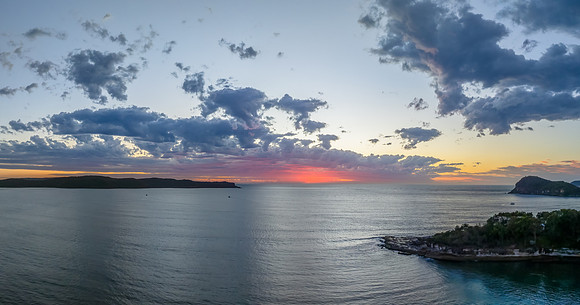 Sunrise over the ocean with clouds and a calm sea