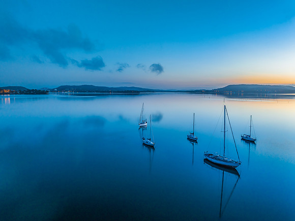 Aerial sunrise waterscape with boats, reflections and low cloud