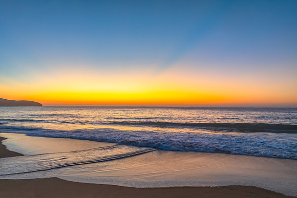 Sunrise seascape with clear skies, orange horizon and sun rays