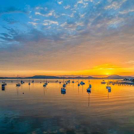 Aerial sunrise over the water with boats and clouds