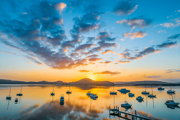 Aerial sunrise waterscape with boats, reflections and low cloud