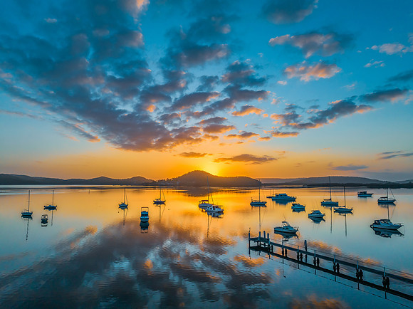 Aerial sunrise waterscape with boats, reflections and low cloud