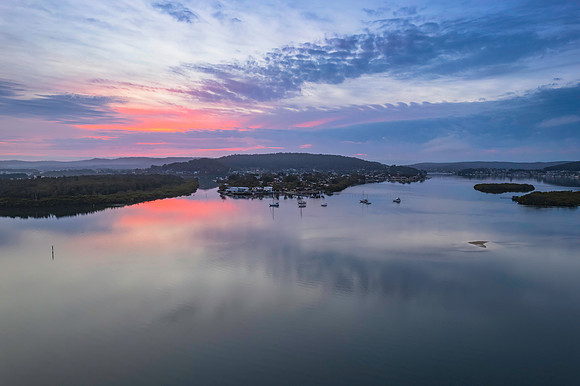 Soft and peaceful sunrise aerial waterscape with clouds and refl