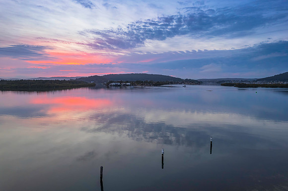 Soft and peaceful sunrise aerial waterscape with clouds and refl