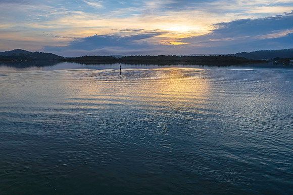 Soft and peaceful sunrise aerial waterscape with clouds and refl