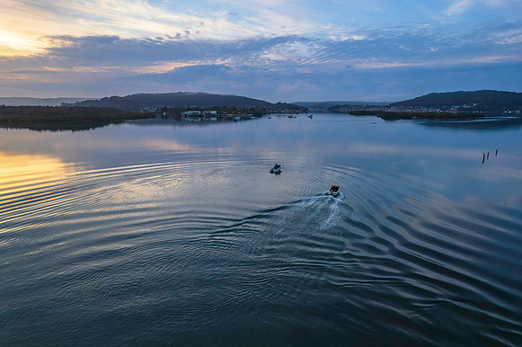 Soft and peaceful sunrise aerial waterscape with clouds and refl