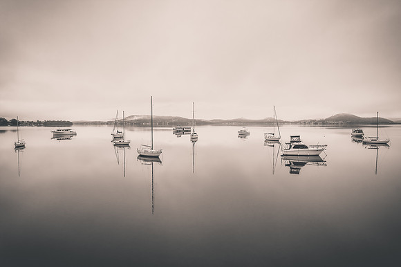 Cloud covered aerial waterscape with boats in monochrome