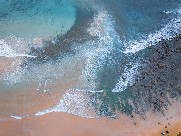 Top down at the seaside with waves, rocks and seaweed