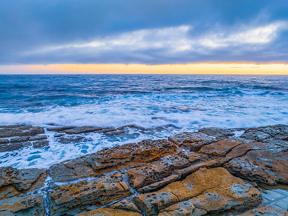 Cloudy sunrise over the ocean with rock platform