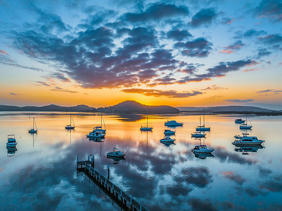 Aerial sunrise waterscape with boats, reflections and low cloud