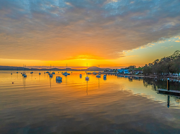 Aerial sunrise over the water with boats and clouds