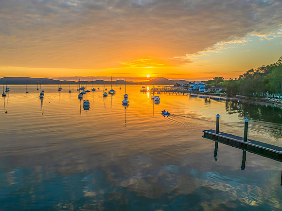 Aerial sunrise over the water with boats and clouds