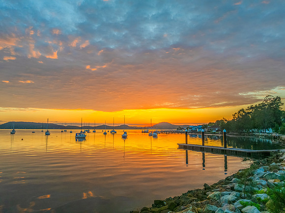 Aerial sunrise over the water with boats and clouds
