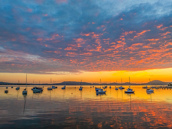 Aerial sunrise over the water with boats and clouds
